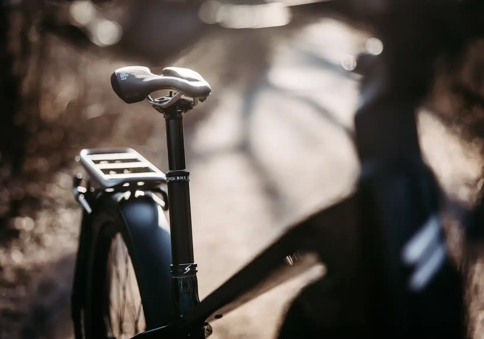 Nahaufnahme des schwarzen Sattels auf einer versenkbaren Sattelstütze eines Simplon Sengo e E-Bikes mit einem silbernen Gepäckträger im Hintergrund.