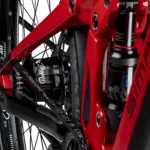 Detailaufnahme des Hinterrads eines roten SIMPLON Stomp SUV :e E-Mountainbikes mit Fokus auf den Rohloff Nabenschalter und den Gates Carbon Drive Riemenantrieb sowie den RockShox Dämpfer.