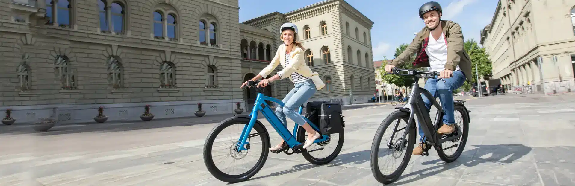 Zwei Menschen fahren auf Stromer ST2 Pinion E-Bikes durch eine städtische Umgebung