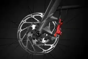 Nahaufnahme einer Scheibenbremse mit rotem Bremssattel und ABS am Vorderrad eines E-Bikes