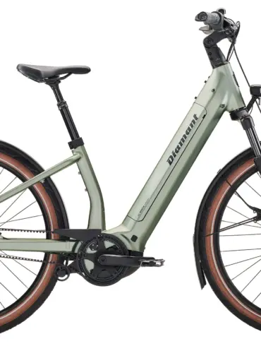 Hellgrünes Diamant Suvea Style 600 Wh Touren-E-Bike mit schwarzem Gepäckträger und orangefarbenen Packsäcken am Lenker.