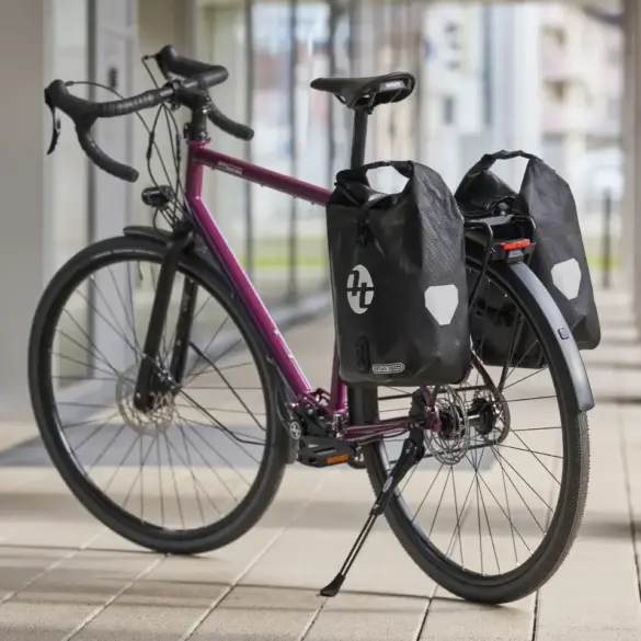Lila Tout Terrain Tribeca Fahrrad mit Rennlenker und Ortlieb-Gepäcktaschen.