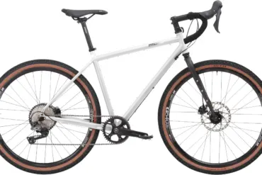 Graues Stahl-Gravelbike mit Dropbar-Lenker, breiten Reifen und Scheibenbremsen, das für Bikepacking und Abenteuer konzipiert ist.