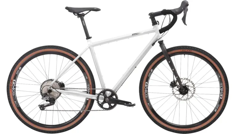 Graues Stahl-Gravelbike mit Dropbar-Lenker, breiten Reifen und Scheibenbremsen, das für Bikepacking und Abenteuer konzipiert ist.