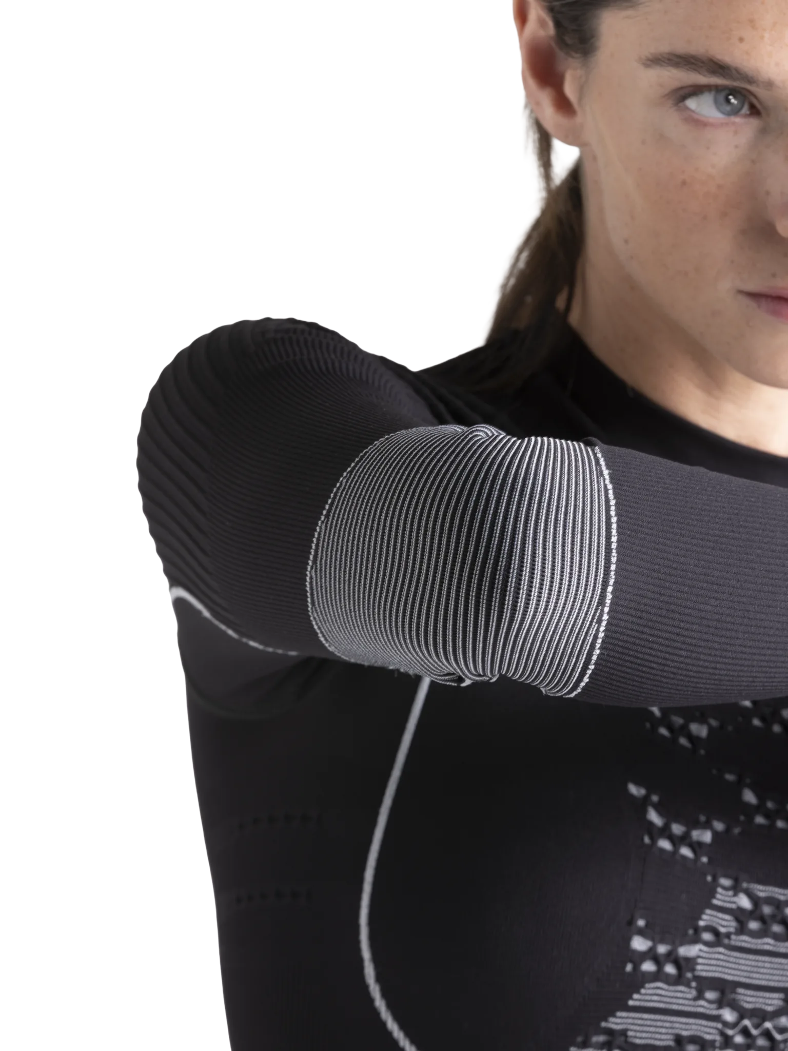 Nahaufnahme des Arms einer Person, die ein schwarzes X-Bionic Energy Accumulator Wild Shirt LS mit weißer Streifenstruktur am Ellbogen trägt.