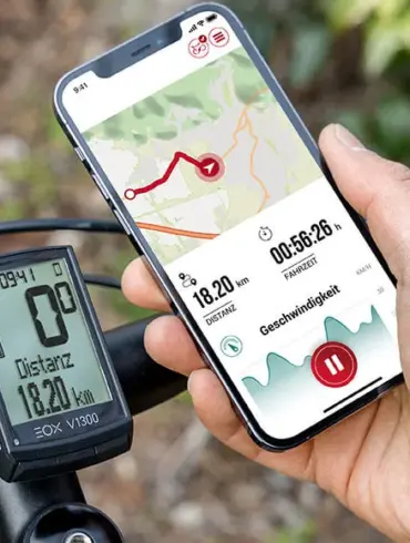 Ein Mann hält ein Smartphone mit der Sigma EOX App, das eine Fahrradroute und Fahrdaten anzeigt, neben einem Sigma EOX VIEW 1300 E-Bike Display, das am Lenker eines Fahrrads montiert ist.