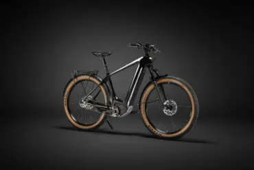 Ein schwarzes Heritage Style Escapade Elektrofahrrad steht freistehend vor einem dunklen Hintergrund.