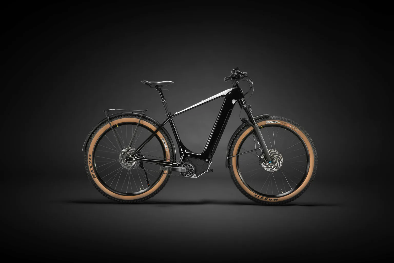 Schwarz lackiertes Heritage Style Escapade E-Bike mit braunen Reifen und Gepäckträgern, stehend auf dunklem Hintergrund.