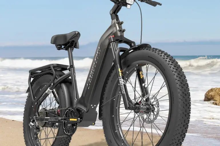 Das Lankeleisi MG600 Plus E-Fatbike steht auf Sand am Strand mit dem Meer im Hintergrund.