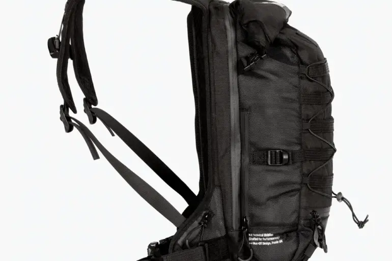 Seitenansicht eines schwarzen Muc-Off Ride Pack Rucksacks mit Molle-System und Rolltop-Verschluss.
