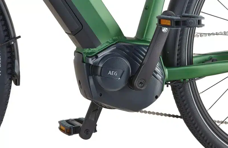 Nahansicht des AEG-Mittelmotors, der Kurbel, des Pedals und des Kettenschutzbügels an einem grünen Prophete Entdecker 4.9 Trekking-E-Bike.