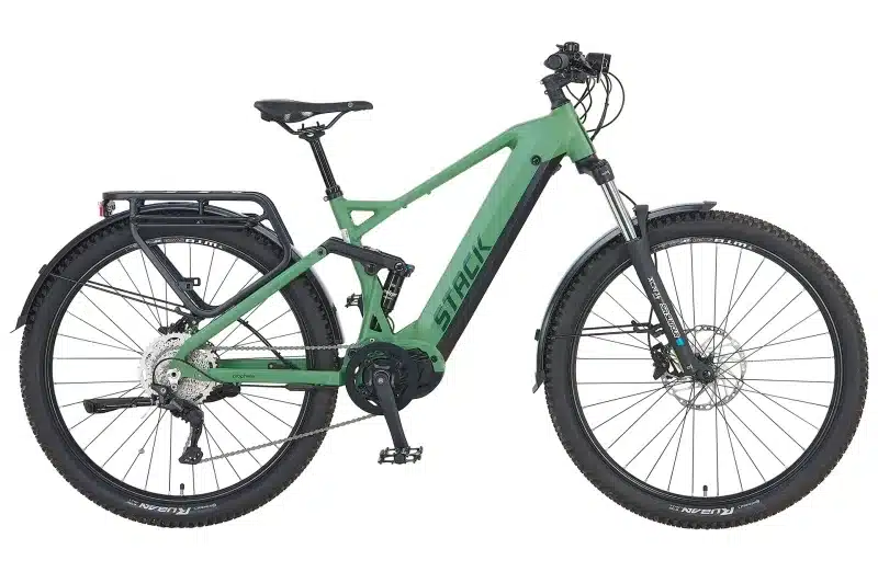 Grünes Prophete Stack 5.0 29 E-Mountainbike mit Mittelmotor, Vollfederung und Gepäckträger, isoliert vor weißem Hintergrund.