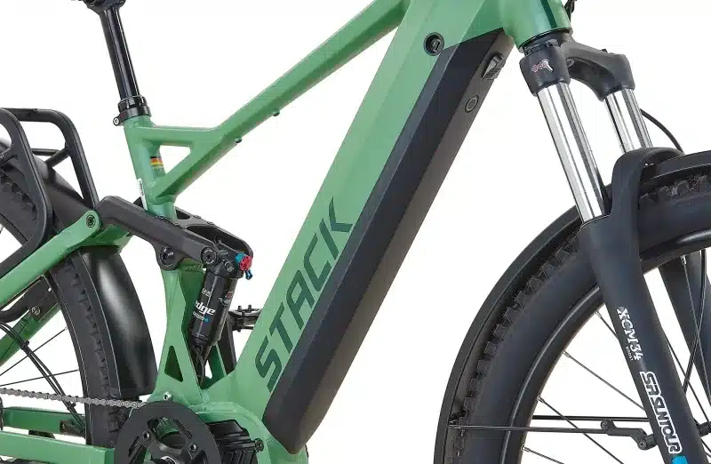 Grünes Prophete Stack 5.0 29 E-MTB im Detail, Fokus auf den Rahmen, den integrierten Akku und die Hinterradfederung.