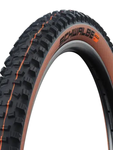 Ein Schwalbe Hans Dampf Super Trail Fahrradreifen mit aggressivem Profil und bronzefarbener Seitenwand, montiert auf einer Felge.