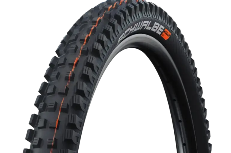 Nahaufnahme des Schwalbe Magic Mary Reifens mit orangefarbenen Akzenten und grobstolligem Profil, geeignet für Downhill und Enduro.