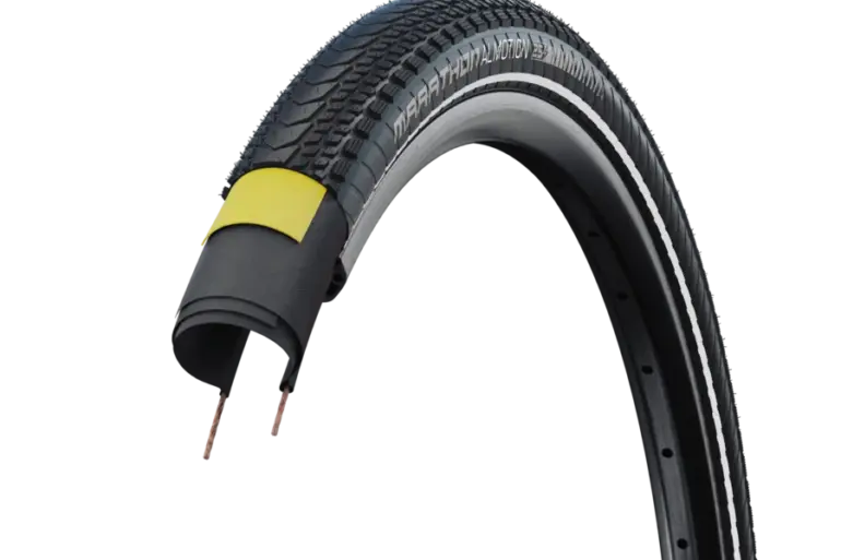 Ein aufgeschnittener Schwalbe Marathon Almotion Tourenreifen, der die Profilierung, die Seitenwand mit "MARATHON ALMOTION E-25" Schriftzug, den pannenschützenden V-Guard und die Karkasse zeigt.