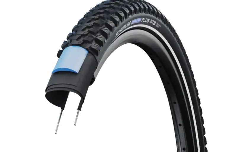 Schnittansicht eines Schwalbe Marathon Plus MTB Fahrradreifens, der die robuste Karkasse und die blaue SmartGuard-Schutzschicht zeigt.