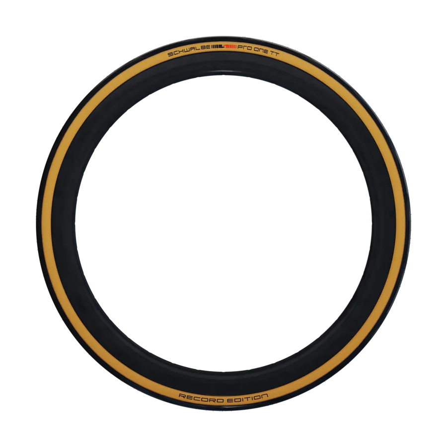 Ein Schwalbe Pro One TT Reifen mit brauner Seitenwand und schwarzem Profil auf schwarzem Hintergrund.