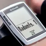 Nahaufnahme eines SIGMA BC 12.0 WR Fahrradcomputers, montiert am Lenker eines Fahrrads. Das Display zeigt Informationen zur Reifengröße.
