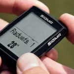 Person hält SIGMA BC 14.0 WL Fahrradcomputer mit Displayanzeige "Radumf. 1 28".