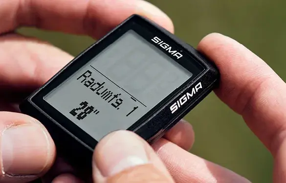 Person hält SIGMA BC 14.0 WL Fahrradcomputer mit Displayanzeige "Radumf. 1 28".