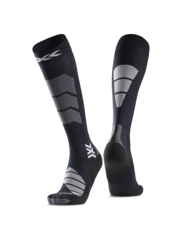 Nahaufnahme eines Paares kniehoher, dunkler Socken mit strategisch platzierten grauen und weißen Verstärkungen und einem Markensymbol.