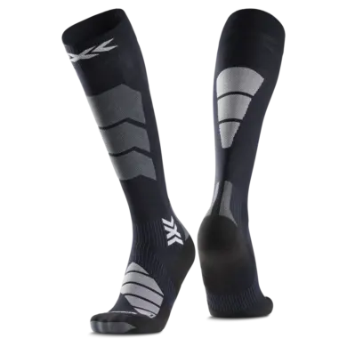 Nahaufnahme eines Paares kniehoher, dunkler Socken mit strategisch platzierten grauen und weißen Verstärkungen und einem Markensymbol.