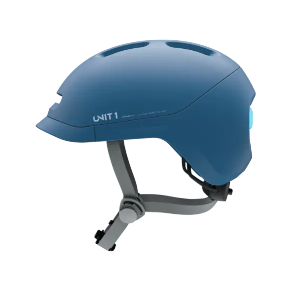 Ein blauer Sparky Junior Kinder-Smart-Helm, liegend auf grünem Hintergrund.