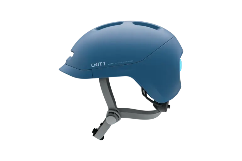 Ein blauer Sparky Junior Kinder-Smart-Helm, liegend auf grünem Hintergrund.