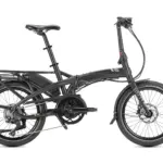 Seitenansicht eines schwarzen Tern Vektron S10 E-Faltrads, das auf weißem Hintergrund steht. Das Fahrrad ist aufgeklappt und zeigt den Bosch Performance Line Antrieb, den integrierten Gepäckträger und die breiten Schwalbe Big Apple Reifen.