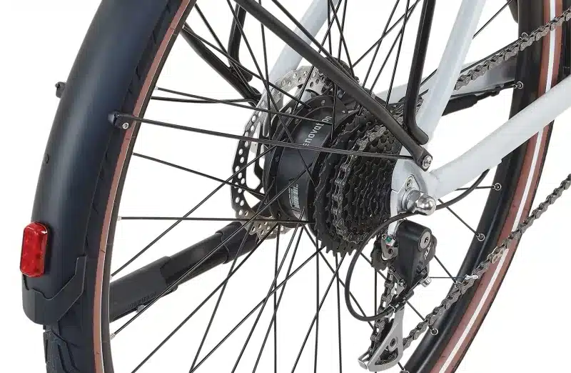 Detailaufnahme des Hinterrads eines Prophete Urbanicer 2.9 E-Bikes mit Fokus auf den integrierten Nabenmotor, das Schaltwerk und die Scheibenbremse.