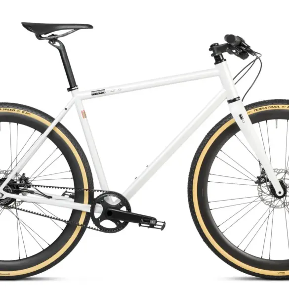 Ein weißes Gravel Bike mit Riemenantrieb und beigen Reifen, stehend vor weißem Hintergrund.