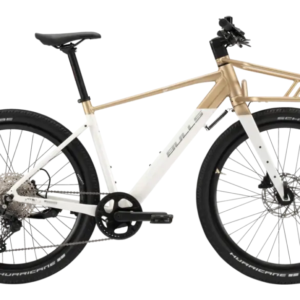 Seitenansicht eines weißen Bulls Clunker Evo E-Bikes mit goldenen Akzenten und einem vorderen Gepäckträger, fotografiert im Studio.