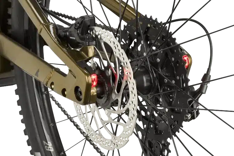 Nahaufnahme des Hinterrads eines BULLS Copperhead EVO 1 Trapez E-Mountainbikes, mit Fokus auf der goldenen Hinterradaufhängung, der Kassette, der Scheibenbremse und den roten Rückleuchten.