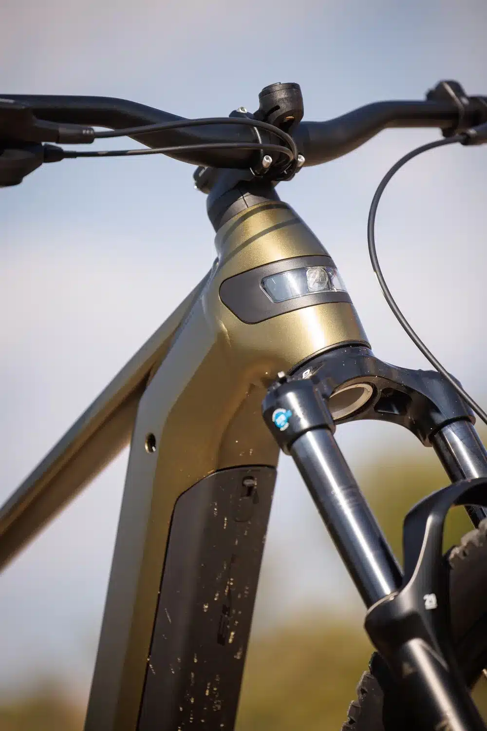 Nahaufnahme des vorderen Rahmenteils eines BULLS Copperhead EVO 29 Trapez E-Mountainbikes, Fokus auf Lenker, Steuerrohr mit integriertem Scheinwerfer und der oberen Hälfte der Federgabel.