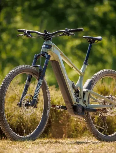 Bulls Copperhead EVO AM 2 E-Mountainbike in olivgrüner Lackierung, mit Federgabel und voller Federung, steht auf einem Feldweg im Grünen.