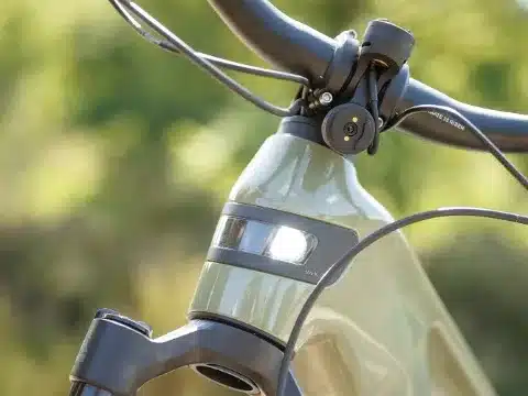 Detailbild eines grünen E-Mountainbikes, das den integrierten Scheinwerfer am Rahmen und eine Halterung am Lenker zeigt