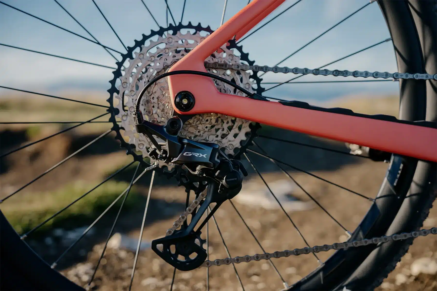 Detailansicht des Shimano GRX Schaltwerks und der Kassette an einem E-Gravelbike mit orangefarbenem Rahmen.