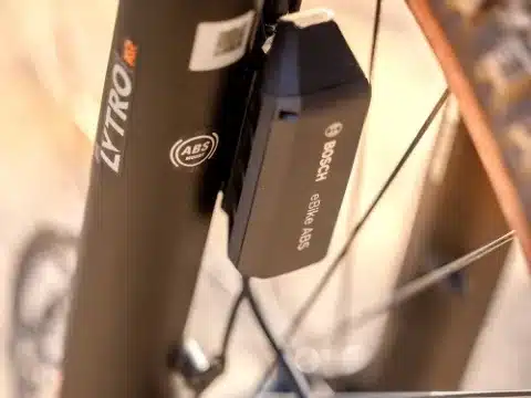 Detailansicht eines Bosch eBike ABS-Moduls, das an den Rahmen eines E-Mountainbikes geschraubt ist, mit Fokus auf den Schriftzug 'Bosch eBike ABS'.