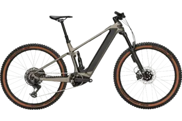 Das BULLS Sonic AM 4 ABS ist ein taupefarbenes E-Mountainbike mit Carbonrahmen und braunen Reifen, das auf einem neutralen grünen Hintergrund steht.