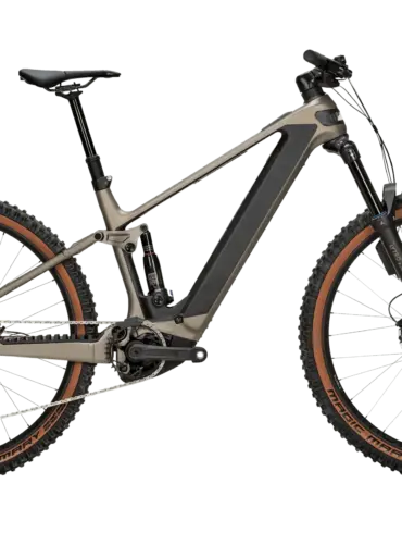 Das BULLS Sonic AM 4 ABS ist ein taupefarbenes E-Mountainbike mit Carbonrahmen und braunen Reifen, das auf einem neutralen grünen Hintergrund steht.