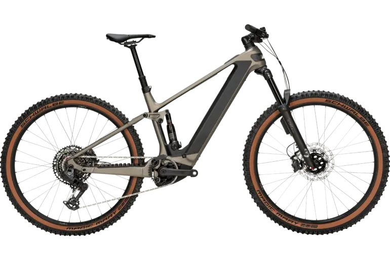 Das BULLS Sonic AM 4 ABS ist ein taupefarbenes E-Mountainbike mit Carbonrahmen und braunen Reifen, das auf einem neutralen grünen Hintergrund steht.