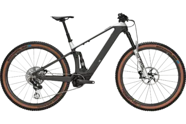 Seitenansicht des BULLS Sonic AM SX I 2024 E-Mountainbikes mit schwarzem Carbonrahmen, silberner RockShox Federgabel und braunen Reifen.