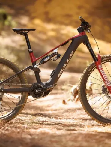BULLS SONIC EN-R TEAM E-Enduro Mountainbike mit Vollcarbon-Rahmen und roter Federgabel, auf einem Waldweg stehend.