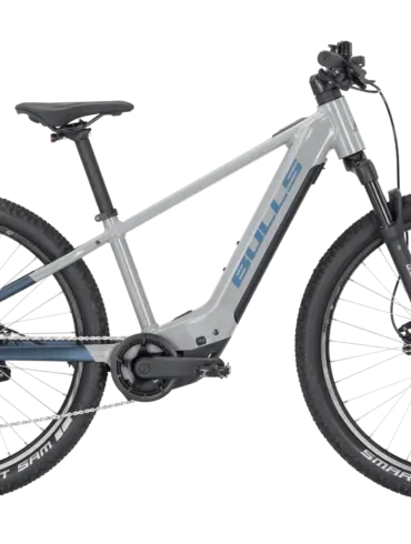 Graues BULLS TOKEE EVO SX 26 E-Mountainbike mit blauen Akzenten und Schwalbe Smart Sam Reifen.