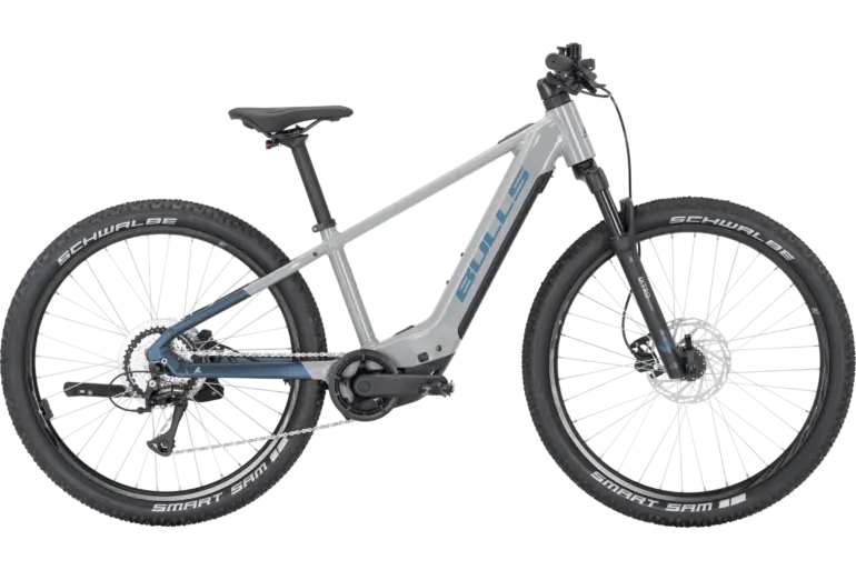 Graues BULLS TOKEE EVO SX 26 E-Mountainbike mit blauen Akzenten und Schwalbe Smart Sam Reifen.