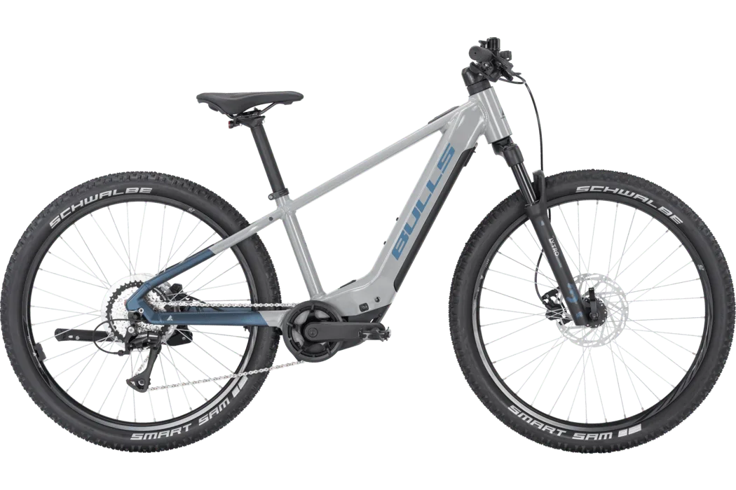 Graues BULLS TOKEE EVO SX 26 E-Bike mit dem BULLS-Logo auf dem Rahmen, der Bosch Performance Line SX Mittelmotor-Einheit und Federgabel.