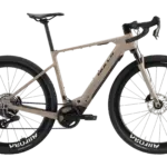 Das BULLS Trail Grinder EVO SX 2025 ist ein E-Gravelbike in einem sandfarbenen Rahmen. Es verfügt über breite Reifen mit der Aufschrift "Mavic Allroad" und "Schwalbe G-One RX", eine RockShox Federgabel und einen Bosch Performance Line SX Motor.