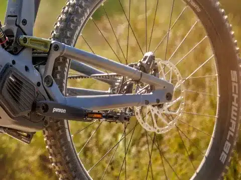 Detailaufnahme des Hinterbaus mit Scheibenbremse, Rad und dem integrierten Pinion Getriebemotor mit Gates-Riemenantrieb eines E-Mountainbikes.