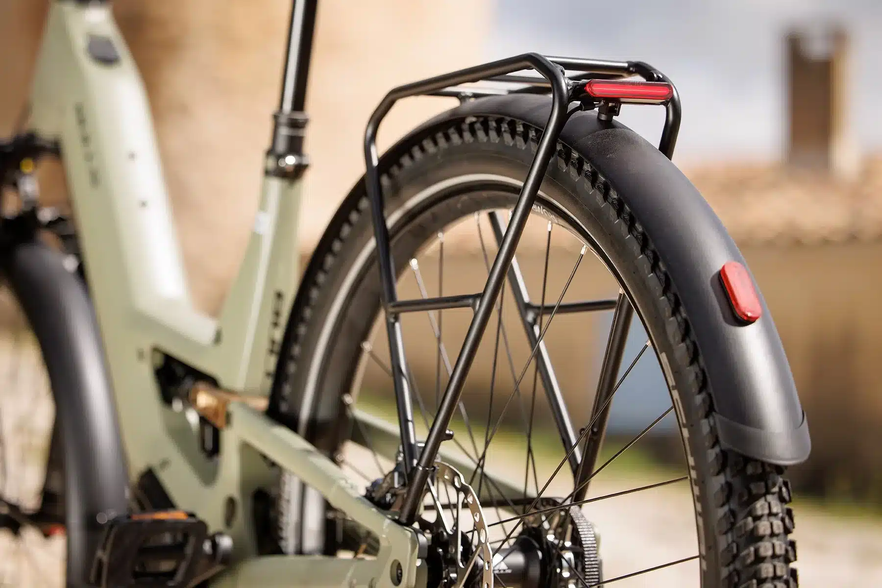 Detailansicht des BULLS VUCA EVO FS 2 E-Bikes, Fokus auf das Hinterrad, den schwarzen Gepäckträger mit integriertem Rücklicht und das mattschwarze Schutzblech.